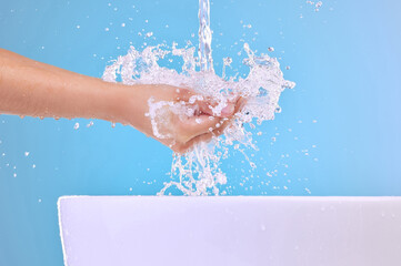 Water splash, model and washing hands in studio for health, hygiene or wellness isolated on blue...