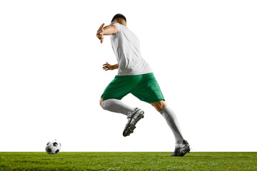 Rear view portrait of young fit man, soccer player ready to kick a soccer ball on green grass field...