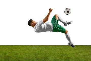 Side view of soccer player performing acrobatic kick with soccer ball in flight above him, against...