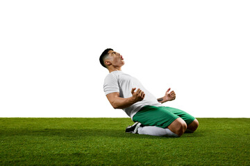 Side view portrait of overjoyed young man kneeling on field clenched fists and look of triumph...