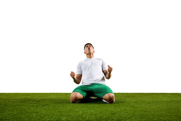 High-energy image of footballer kneeling on grassland with fists raised in celebration against...