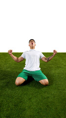 Dynamic shot of soccer player in moment of victory as he kneels on grass with both fists clenched...