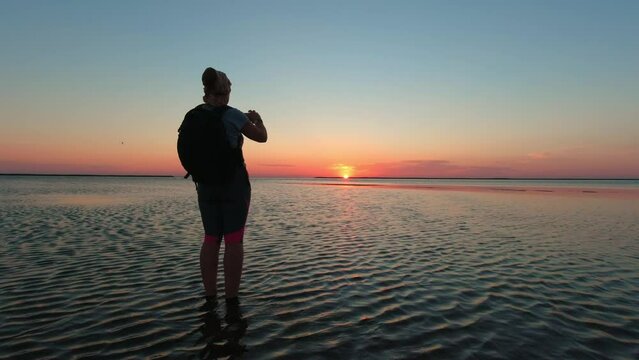 A woman films the sunrise over Kinburn Spit on an early summer morning
