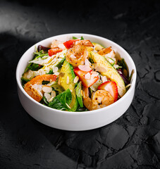 Fresh shrimp and strawberry salad on dark background