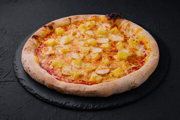 Hawaiian pizza on black slate