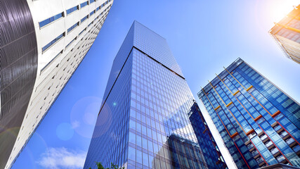 Bottom view of modern skyscrapers in business district against blue sky. Looking up at business buildings in downtown.