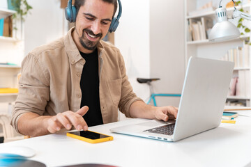 Smiling business man working on laptop at home office. Young student or remote teacher using computer remote studying, virtual training, watching online education webinar at home office. High quality