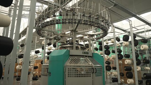 Knitting machines at textile factory. Vertical installation of circular knitting machines with spools of yarn. Concept of textile knitting technology
