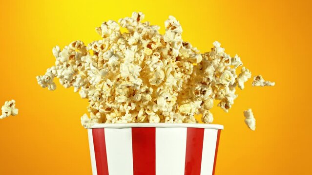 Super Slow Motion of Exploding popcorn from Bucket. Isolated on Red Background. Studio Shot of Flying Food. Filmed on High Speed Cinema Camera, 1000fps.
