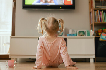 Portrait of happy baby playing with toys and watches cartoons on TV in playroom. Children and technology concept. Alpha Generation and modern technology with electronic device. Part of the series