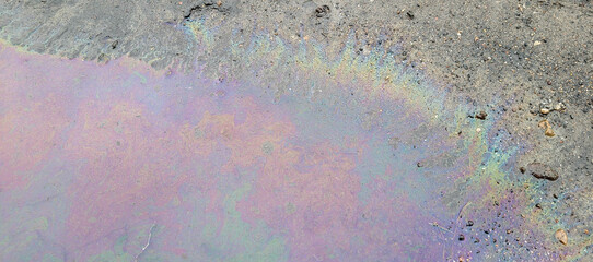 A large rainbow puddle of spilled petroleum product on the road. The concept of environmental...