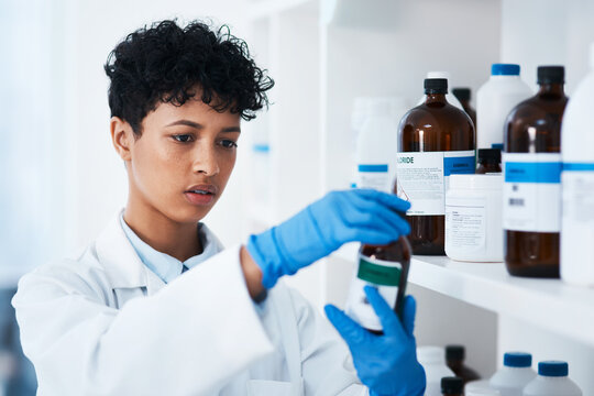 Pharmacy, doctor and woman with bottle of medicine, choice and reading of label for information. Clinic, medical and scientist with supplements, gloves and product for healthcare, wellness and help