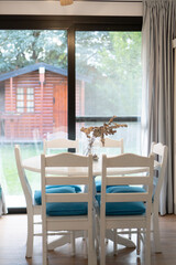 dining room with white table and chairs with a window looking out onto the garden, vertical view