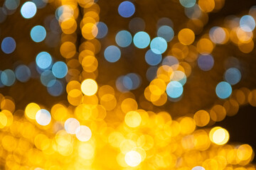 Blurred Christmas black background with bokeh in yellow blue colors.