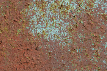 Detailed view of a rusty, cracked metal surface with peeling paint, showcasing textures and patterns of corrosion.