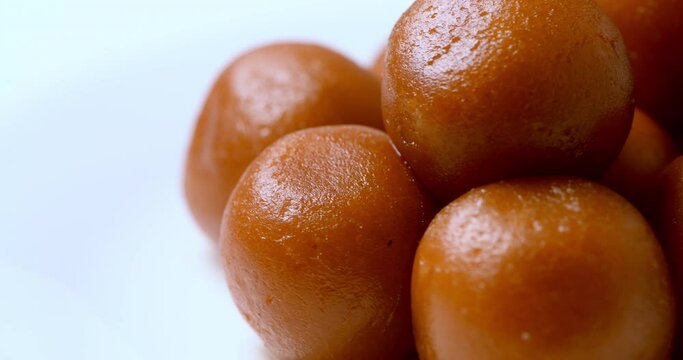 Gulab Jamun indian sweets Closeup in a white plate , rotating slowly. Neatly stacked delicious and mouth watering gulab jamuns. Celebratory indian sweet dish. 