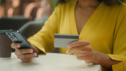 Close up young African American woman holding smartphone mobile phone bank card payment shopping buy happy female satisfied cash credit currency debit finance money purchase online transaction gadget