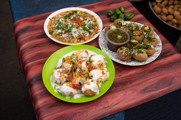 Spicy Chotpoti, plain or Doi Fuchka, pan puri, or gol gappa filled with herbs with spicy water served in plate isolated on wooden table side view of bangladeshi street food © Food Shop