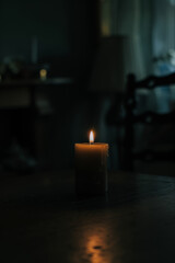 Thick Wax Candle with a Flickering Flame in a Dimly Lit Room
