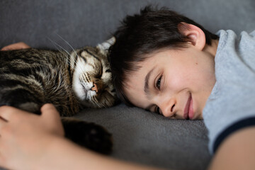 Portrait of little adorable gray cat and little boy indoors
