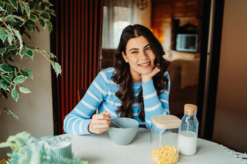 One young caucasian woman is eating corn flex breakfast at home before work	
