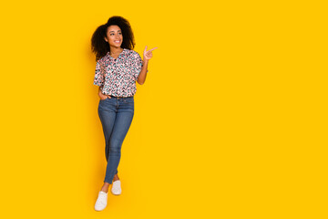 Full length photo of lovely young lady look point empty space dressed stylish leopard print garment isolated on yellow color background