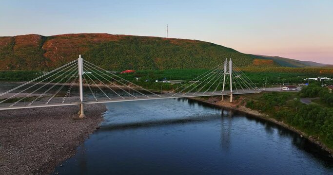 Drone flying in front of the Sami Bridge and Teno river, summer sunset in Utsjoki