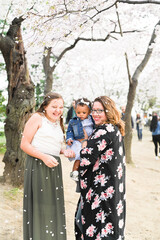 Three women enjoying a cherry blossom festival, with falling pet