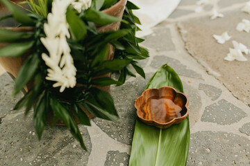 Tropical Leis and wooden water bowl on greens before wedding