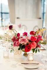 Table centerpiece with pink and red flowers, candles, and table number