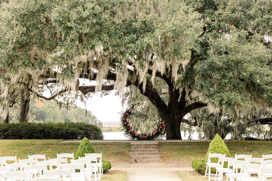 Outdoor wedding ceremony setup under oak tree with floral arch