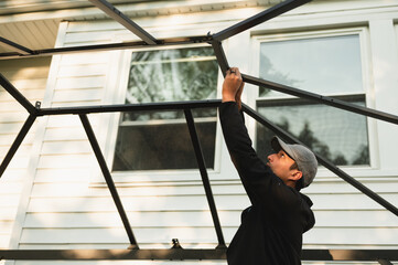 Young man installing metal gazebo frame in backyard of home