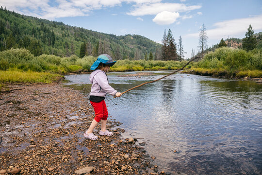 Child playing by a river in a scenic mountain landscape
