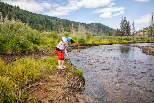 Child exploring riverbank in scenic countryside on a sunny day
