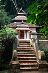 Small buddhist temple nestled amongst green trees in Thailand