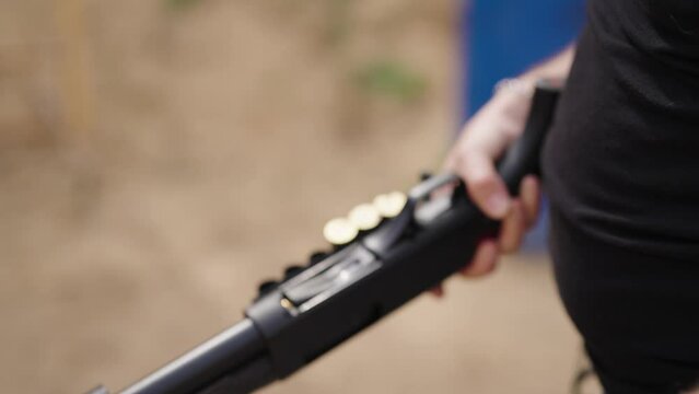 Guy with shotgun reload new shotshells into barrel chamber, shooting range