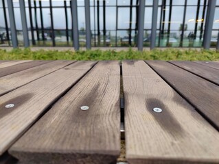 Close-Up of Weathered Wooden Bench with Natural Grain in Front of Modern Glass Building