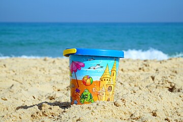 Colored  bucket on the sand near the seashore