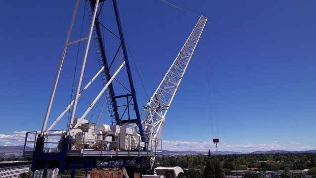 Shot of a blue and white crawler crane lowering down an item.