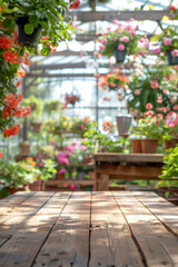 Obraz premium A wooden potting bench in the foreground with a blurred background of a botanical greenhouse. The background includes various potted plants, hanging flowers, gardening tools, and large glass windows