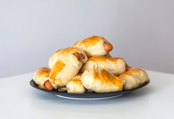 Sausages in the dough on ceramic plate on the table.