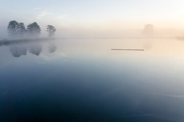 Misty Lake surrounded by tree-covered shores