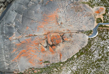 an orange lichen covered rock sitting on top of a field