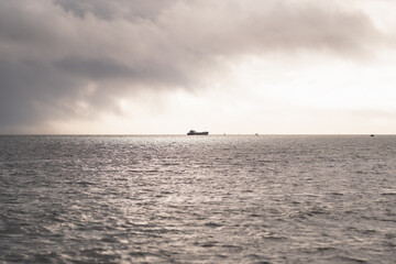 Serene ocean with a ship in the distance on a cloudy day