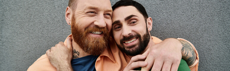 A portrait of a gay couple standing next to each other, exuding love and solidarity against a grey...