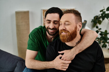 An affectionate moment between two men embracing in a living room filled with moving boxes,...