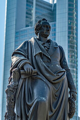 Fototapeta premium a statue of a person is in front of the tall buildings
