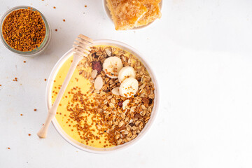 Healthy superfood fruit smoothie bowl with bee pollen, golden creamy shake or smoothie, with granola and banana. Clean eating, dieting vegetarian dish with bee pollen superfood organic powder 