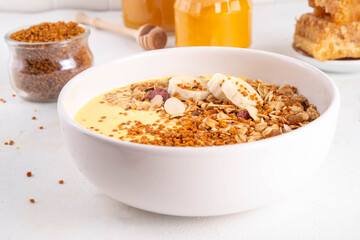 Healthy superfood fruit smoothie bowl with bee pollen, golden creamy shake or smoothie, with granola and banana. Clean eating, dieting vegetarian dish with bee pollen superfood organic powder 