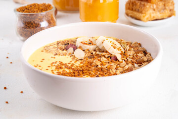 Healthy superfood fruit smoothie bowl with bee pollen, golden creamy shake or smoothie, with granola and banana. Clean eating, dieting vegetarian dish with bee pollen superfood organic powder 